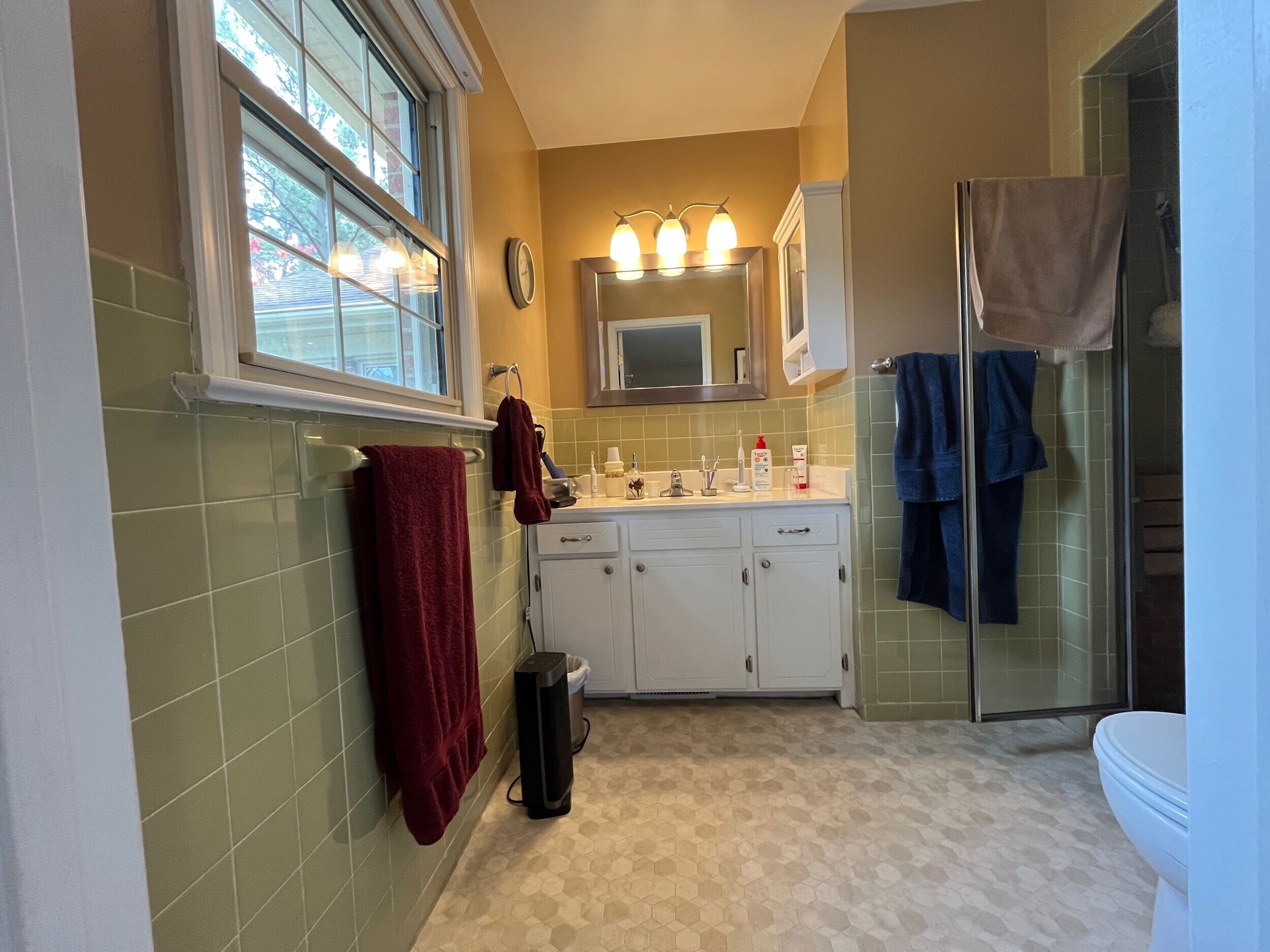 Outdated primary bathroom before renovation featuring old tile flooring, dated fixtures, and an inefficient layout.