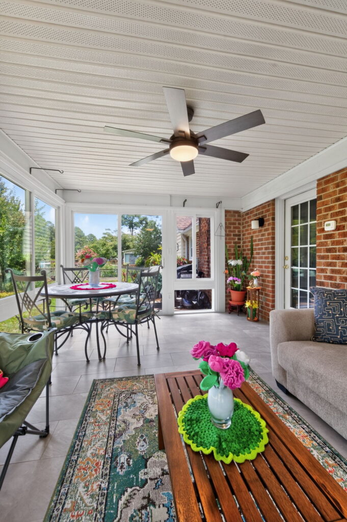 Interior of a Betterliving sunroom with expansive insulated windows overlooking a landscaped backyard.