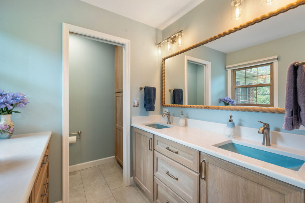 White oak Shiloh double vanity with straw stain, quartz countertops, Native Trails stone sinks, and coastal-inspired finishes.