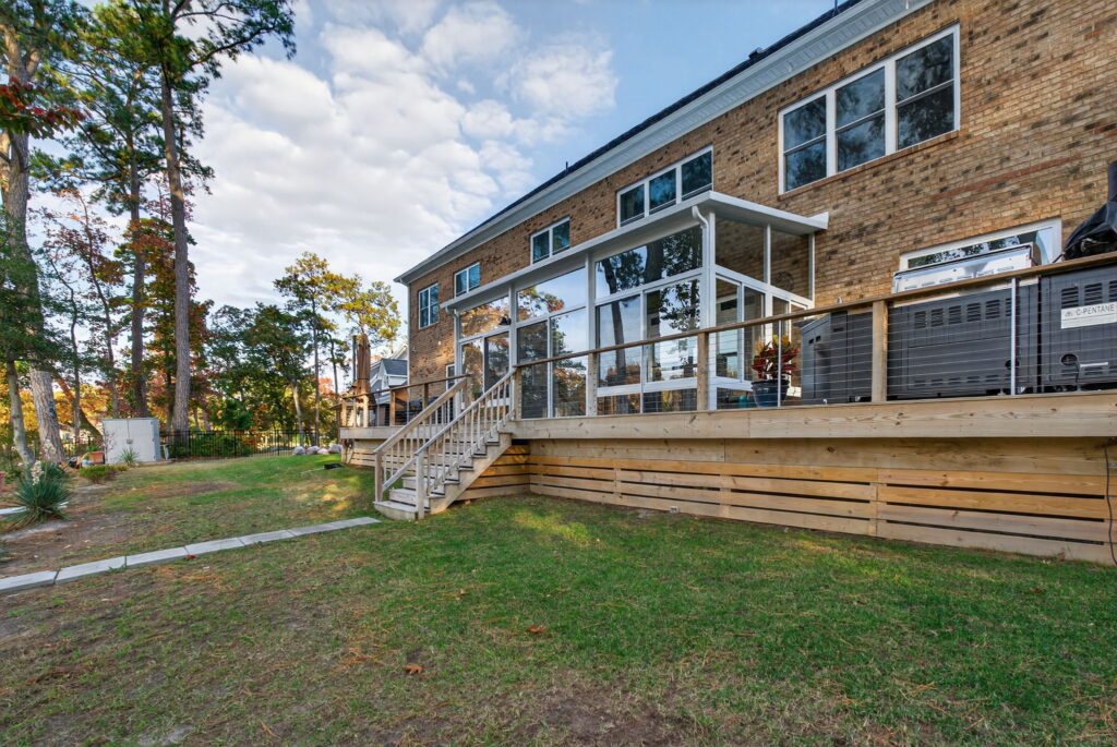 Rear exterior of the home highlighting the newly added Betterliving 3-season sunroom and upgraded deck structure.