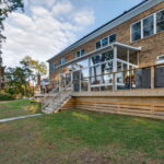 Rear exterior of the home highlighting the newly added Betterliving 3-season sunroom and upgraded deck structure.