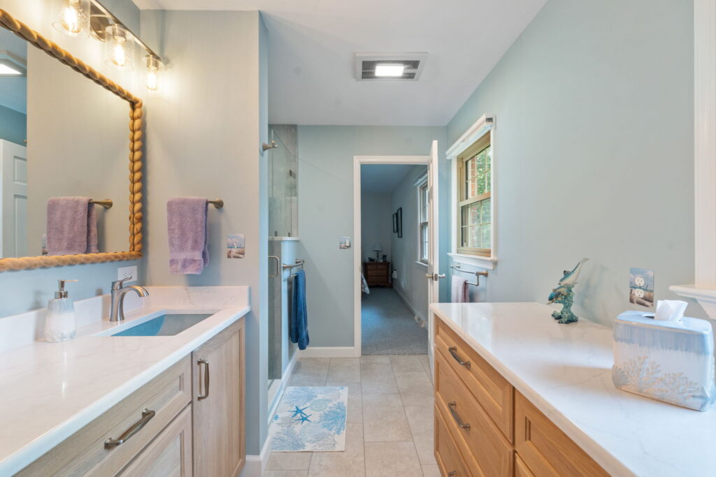 Coastal-inspired primary bathroom featuring accessible design elements, luxury vinyl tile flooring, and stylish safety grab bars.
