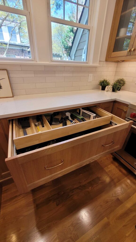 Smart storage touches—like hidden top-drawer shelves, a pull-out trash cabinet, tall pantry towers, and corner lazy susans—maximize efficiency without sacrificing style.