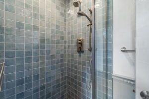Utility bathroom shower with Cielo Zellige ceramic wall tile, Moroccan porcelain floor tile, and glass shower door.