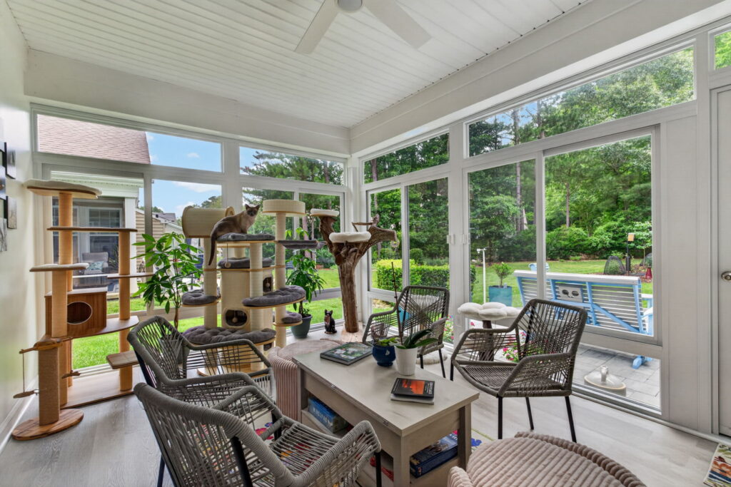 Betterliving sunroom featuring cat climbing towers and large windows overlooking birds and wildlife.