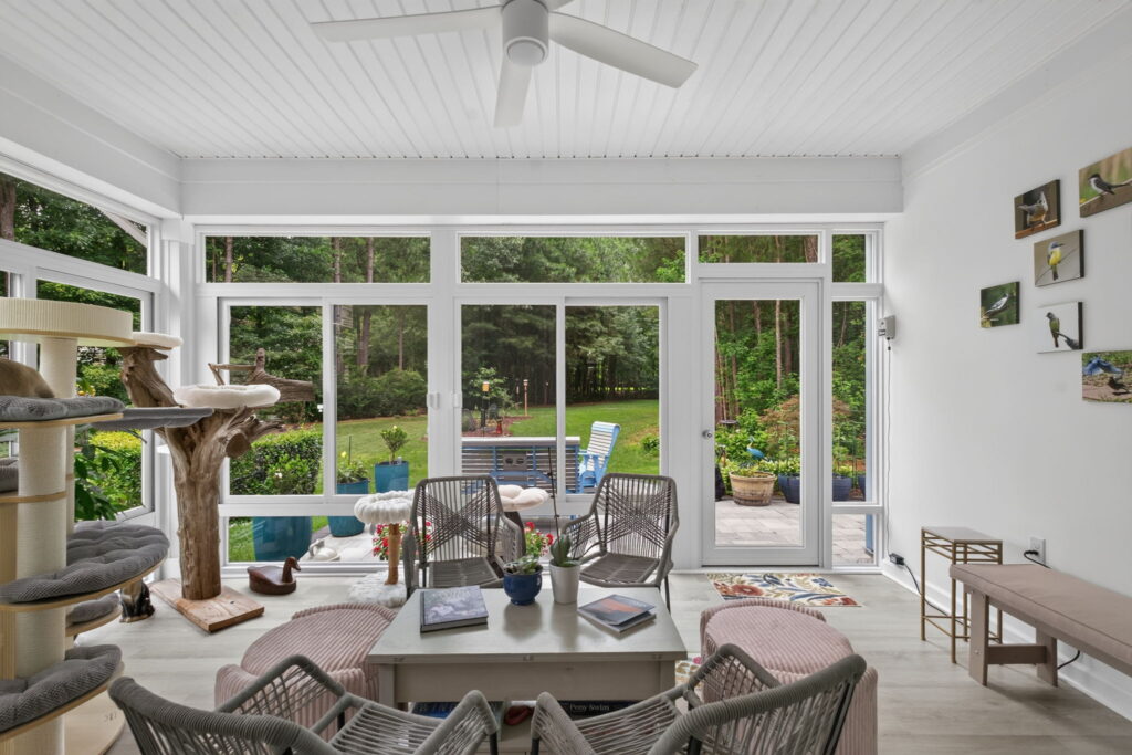 Expansive windows providing scenic wooded backyard views from a 3-season sunroom.