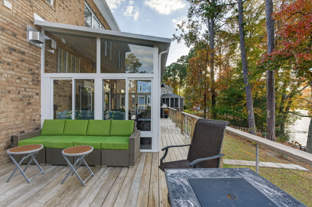 EOutdoor entertaining area adjacent to the Betterliving 3-season sunroom, ideal for grilling and dining with a lake view.